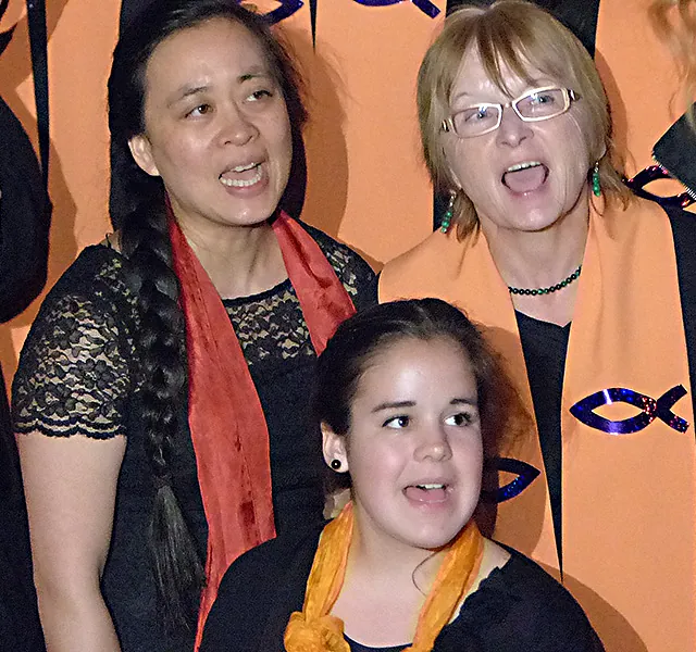 Drei Frauen unterschiedlichen Alters singen mit offenem Mund.