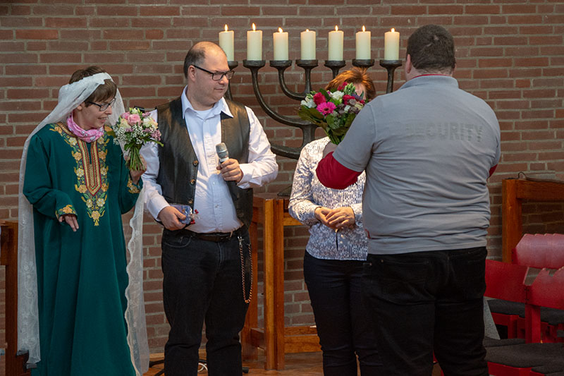 Menschen versammelten sich zu einer Zeremonie mit Blumen, Kerzen und einem Anwesenden.