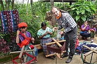 Mann und zwei Frauen weben traditionell im Freien.