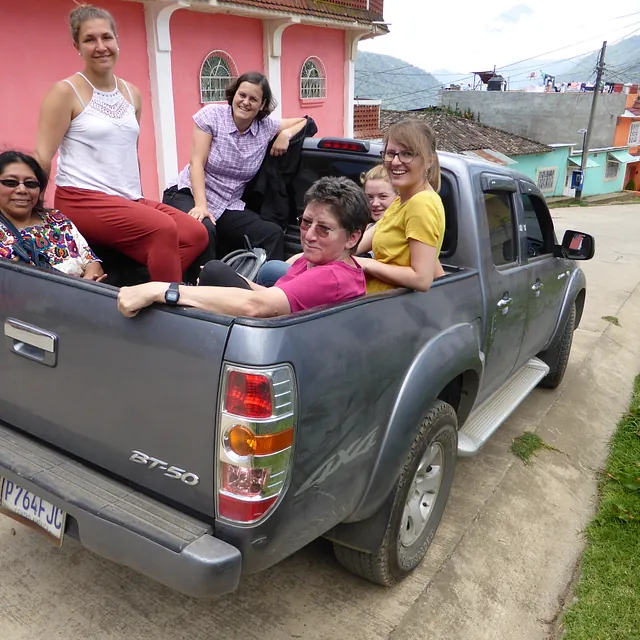 Mehrere Personen fahren auf der Ladefläche eines Pick-up-Trucks.