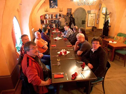 Gruppe von Personen an langem Tisch in warm beleuchtetem Restaurant.