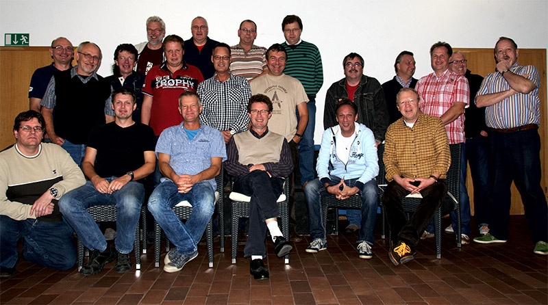 Eine große Gruppe Männer posiert zusammen in einem Raum.