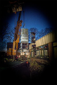 Kran hebt nachts großes weißes Modul.