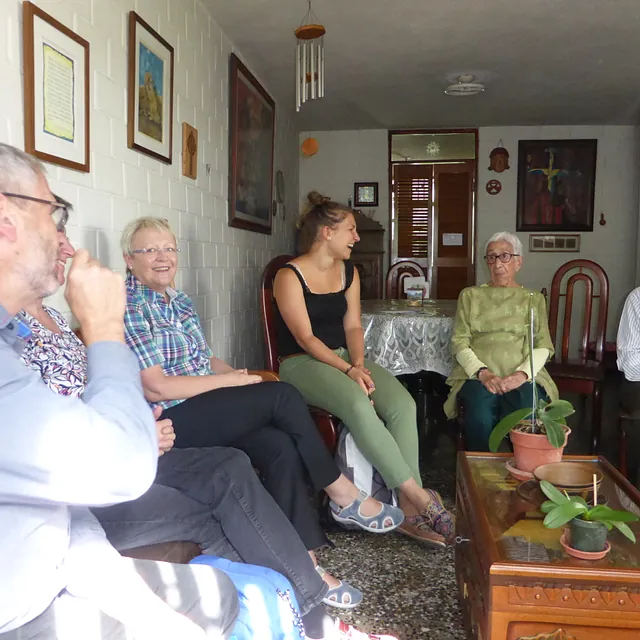 Vielfältige Personengruppe sitzt und unterhält sich in einem Wohnzimmer.