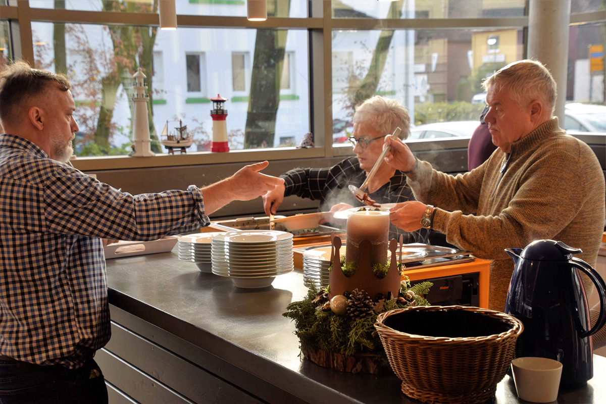 Leute servieren Essen bei einem Gemeinschaftstreffen, gemütliche Atmosphäre.