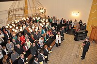 Große Gemeinde versammelt sich zum Gottesdienst in geräumigem Saal.