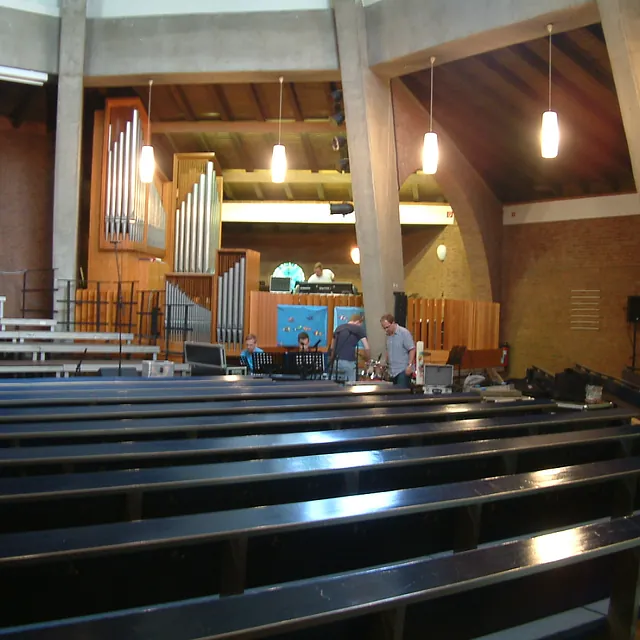 Kircheninneres mit Bänken, Orgel und Personen bei Veranstaltungsvorbereitungen.