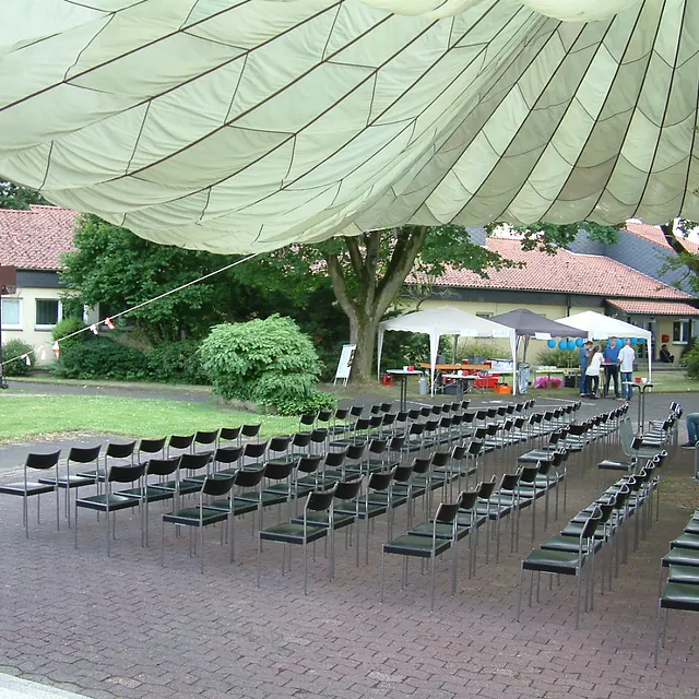 Leere Stühle unter großem Vordach für Außenveranstaltung.