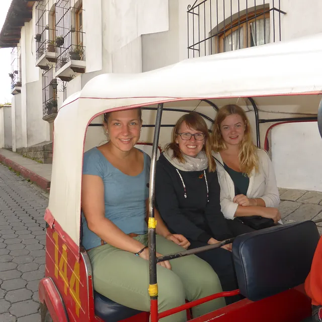 Drei lächelnde Frauen in rotem Tuk-Tuk auf der Straße.