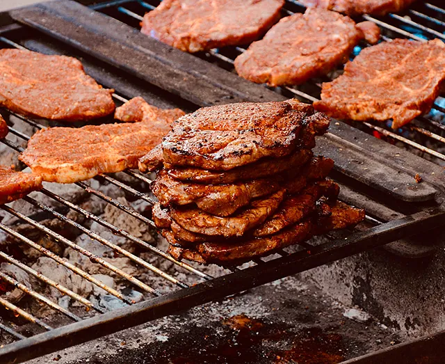 Saftige Schweinekoteletts grillen über glühender Kohle, perfekter Grillmoment.