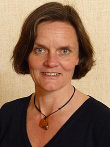 Frau mit braunen Haaren, blauen Augen und Bernsteinanhänger.