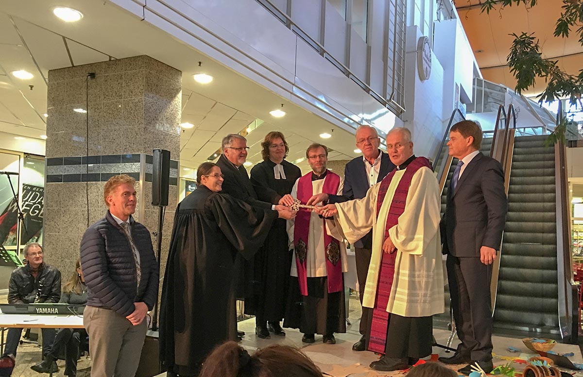 Gruppe von Personen in Roben und Anzügen hält einen zeremoniellen Schlüssel.