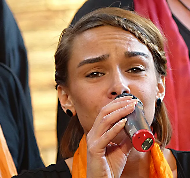 Junge Frau mit geflochtenem Haar singt in ein Mikrofon.