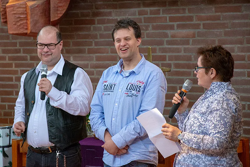 Drei Erwachsene, zwei Männer und eine Frau, mit Mikrofonen.