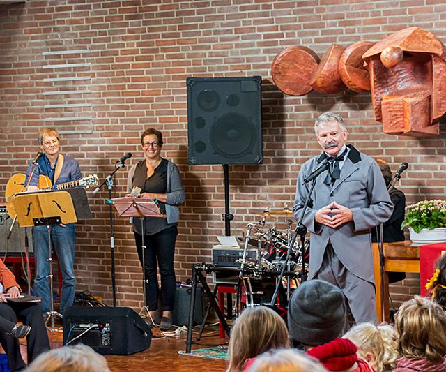 Musiker treten auf der Bühne vor Publikum in einem Ziegelraum auf.