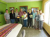 Gruppe von Personen mit Büchern in einem hellgrünen Raum.