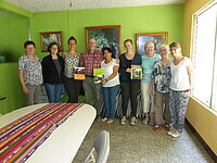 Gruppe von Personen mit Büchern in einem hellgrünen Raum.