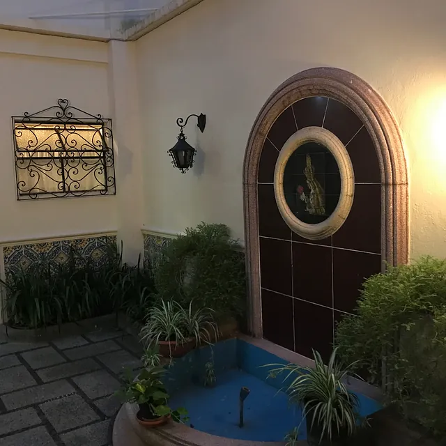 Außenhof mit Springbrunnen, Pflanzen und dekorativem Torbogen.
