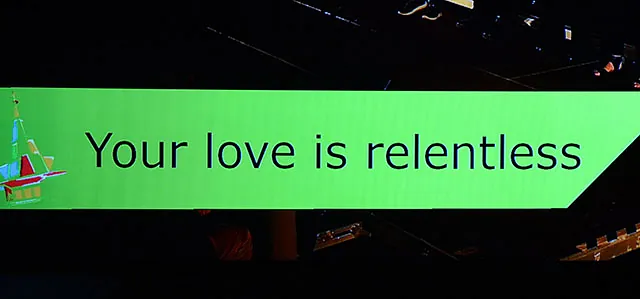 Grünes Banner zeigt "Your love is relentless" mit abstrakter Grafik.