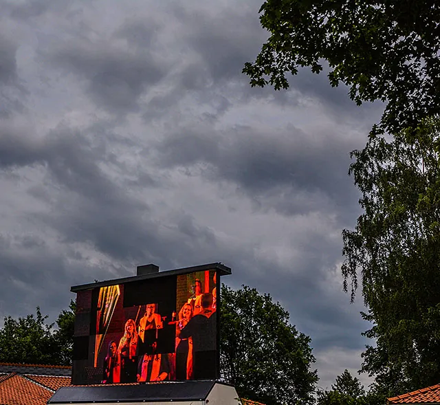 Outdoor-LED-Leinwand zeigt Chorauftritt unter dramatischem Himmel.