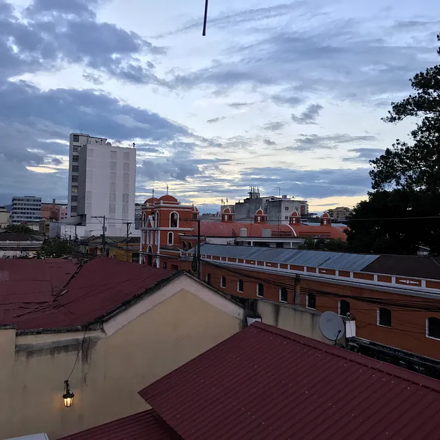 Stadtansicht in der Dämmerung mit verschiedenen Gebäuden und bewölktem Himmel.