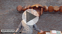 Martin Giesler vor Backsteinwand, Holzkunstwerk, Video-Vorschau.