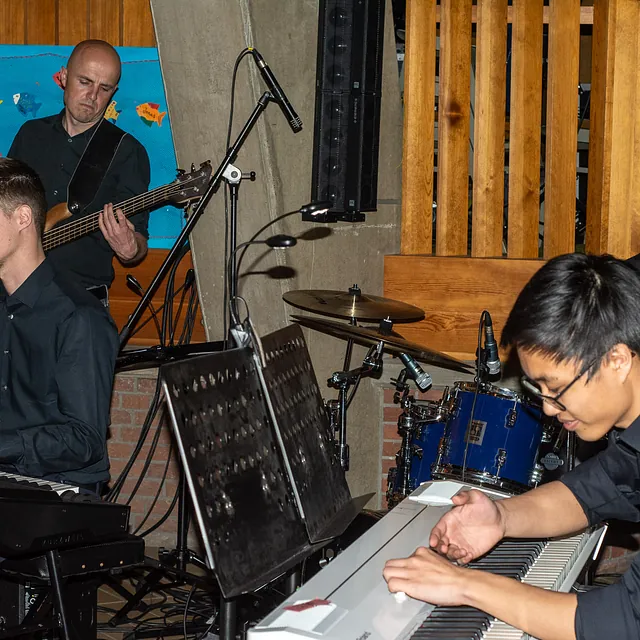 Vier männliche Musiker spielen Keyboard, Bass und Schlagzeug bei Auftritt.