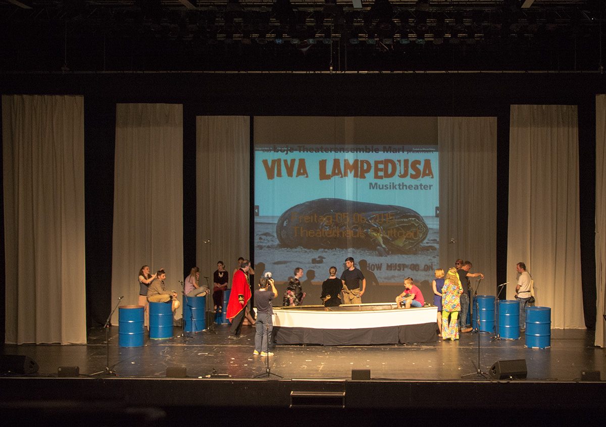 "Viva Lampedusa" Musiktheateraufführung mit Besetzung und Bootsrequisite.