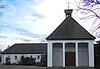 Moderne Kirche mit Glockenturm und weißen Säulen.