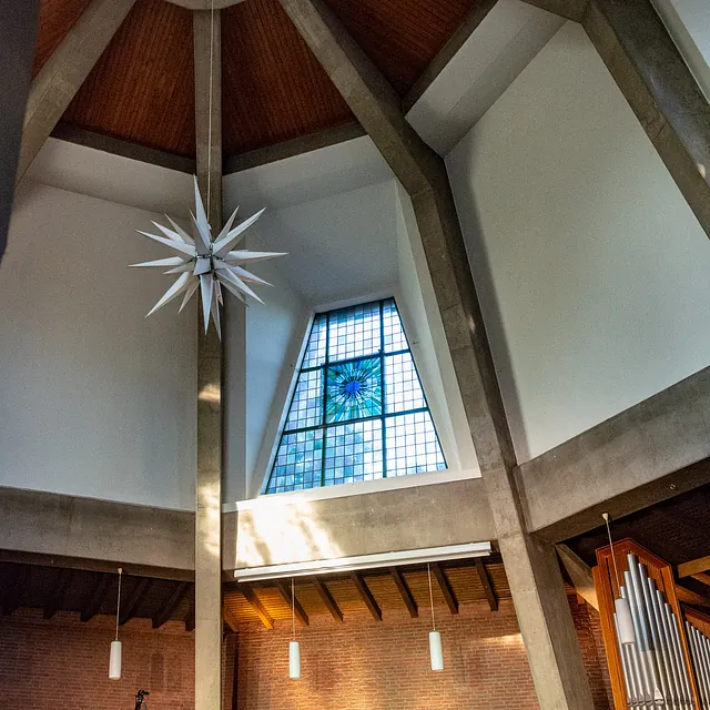 Chor tritt in moderner Kirche mit beeindruckendem Buntglasfenster auf.