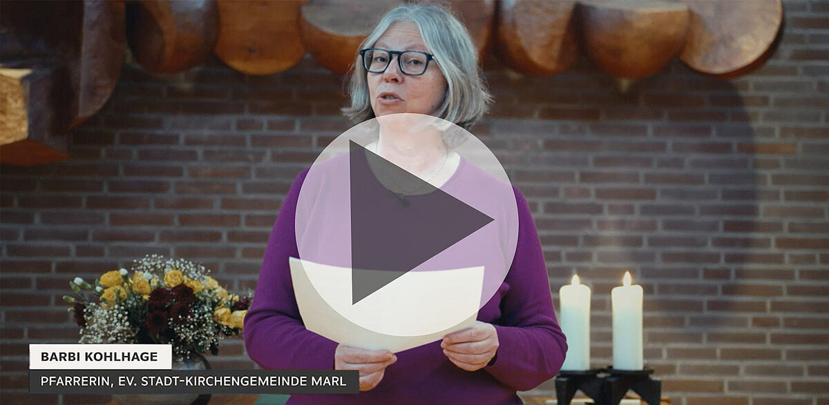 Barbi Kohlhage, Pfarrerin, spricht in Kirche mit Blumen und Kerzen.