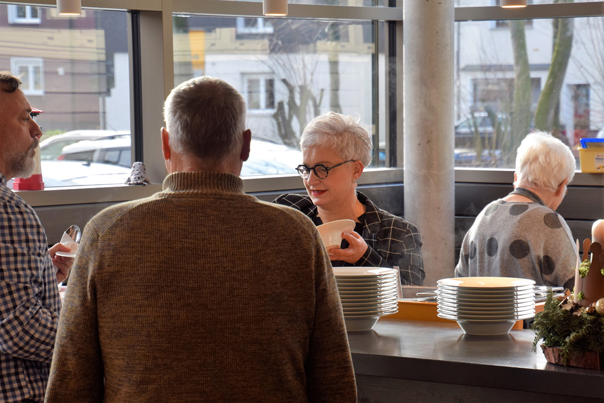 Menschen interagieren und servieren Essen in einer hellen, modernen Umgebung.