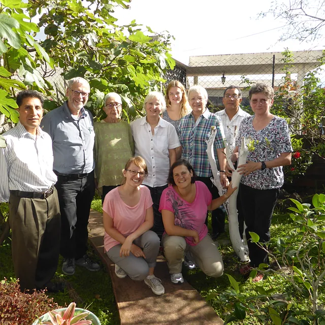 Eine vielfältige Gruppe Erwachsener lächelt in einem sonnigen Garten.