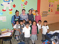 Lehrerinnen und junge Schüler posieren gemeinsam in einem farbenfrohen Klassenzimmer.