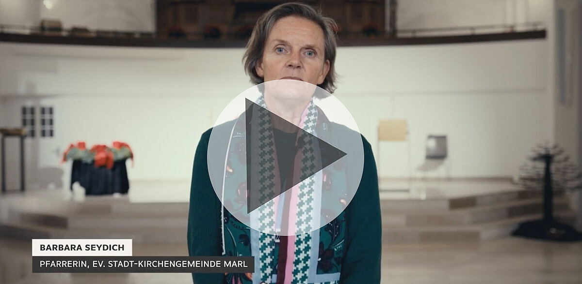 Pfarrerin Barbara Seydich steht in Kirche und spricht Zuschauer an.