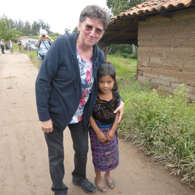 Eine erwachsene Frau mit kurzen Haaren umarmt ein junges Mädchen im Freien.