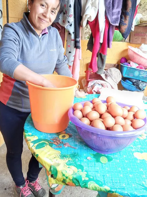 Frau lächelt beim Zubereiten von Eiern an einem Marktstand.