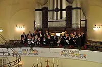 Chor singt in einer Kirche, große Orgel sichtbar.