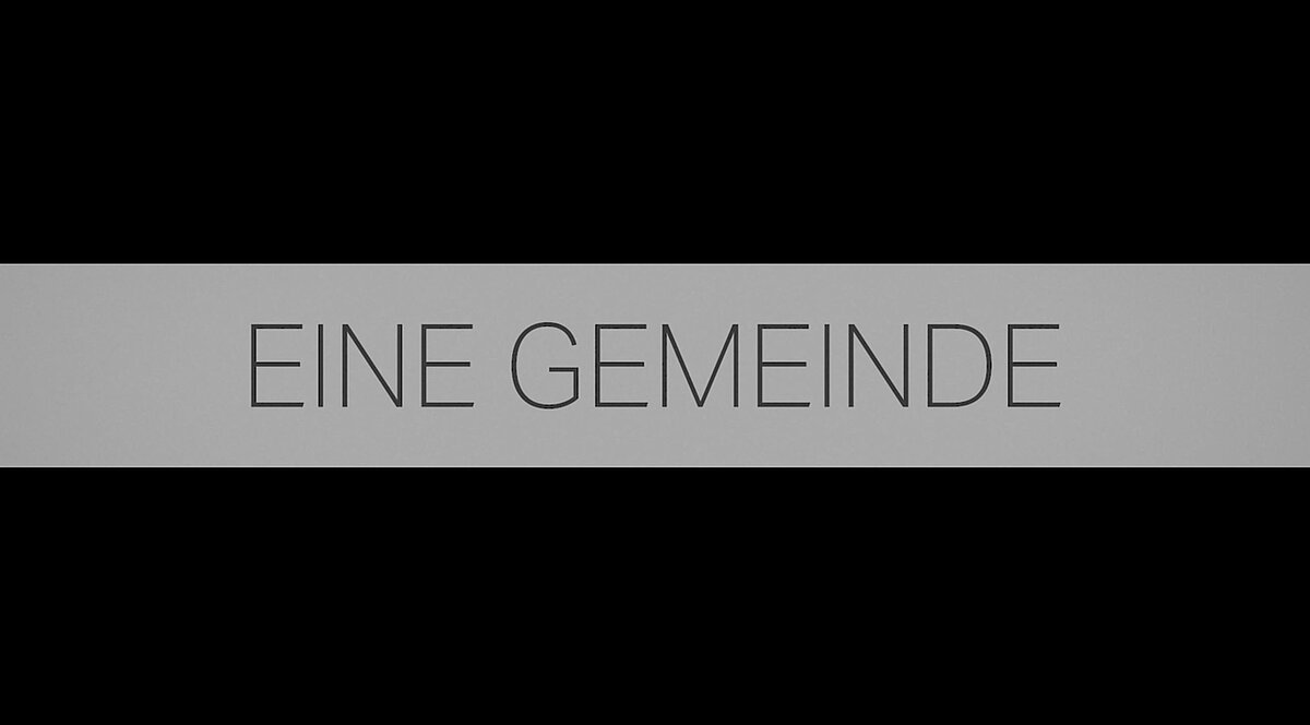 "Eine Gemeinde" (Eine Gemeinde) auf grauem Banner.