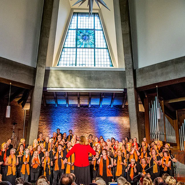 Großer Chor tritt in moderner Kirche mit hohen Decken auf.