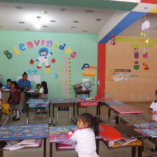 Buntes Klassenzimmer mit Kindern und Lehrerin, verzierten Wänden, Schreibtischen.