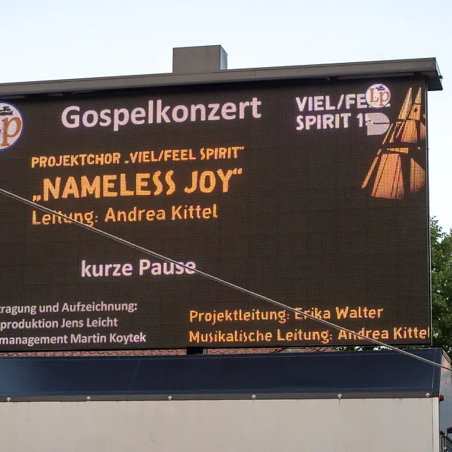 Digitale Werbetafel zeigt „Gospelkonzert Nameless Joy“ und Produktionsinformationen.