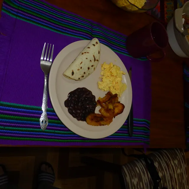 Traditioneller Frühstücksteller mit Tortilla, Eiern, Bohnen und Kochbananen.