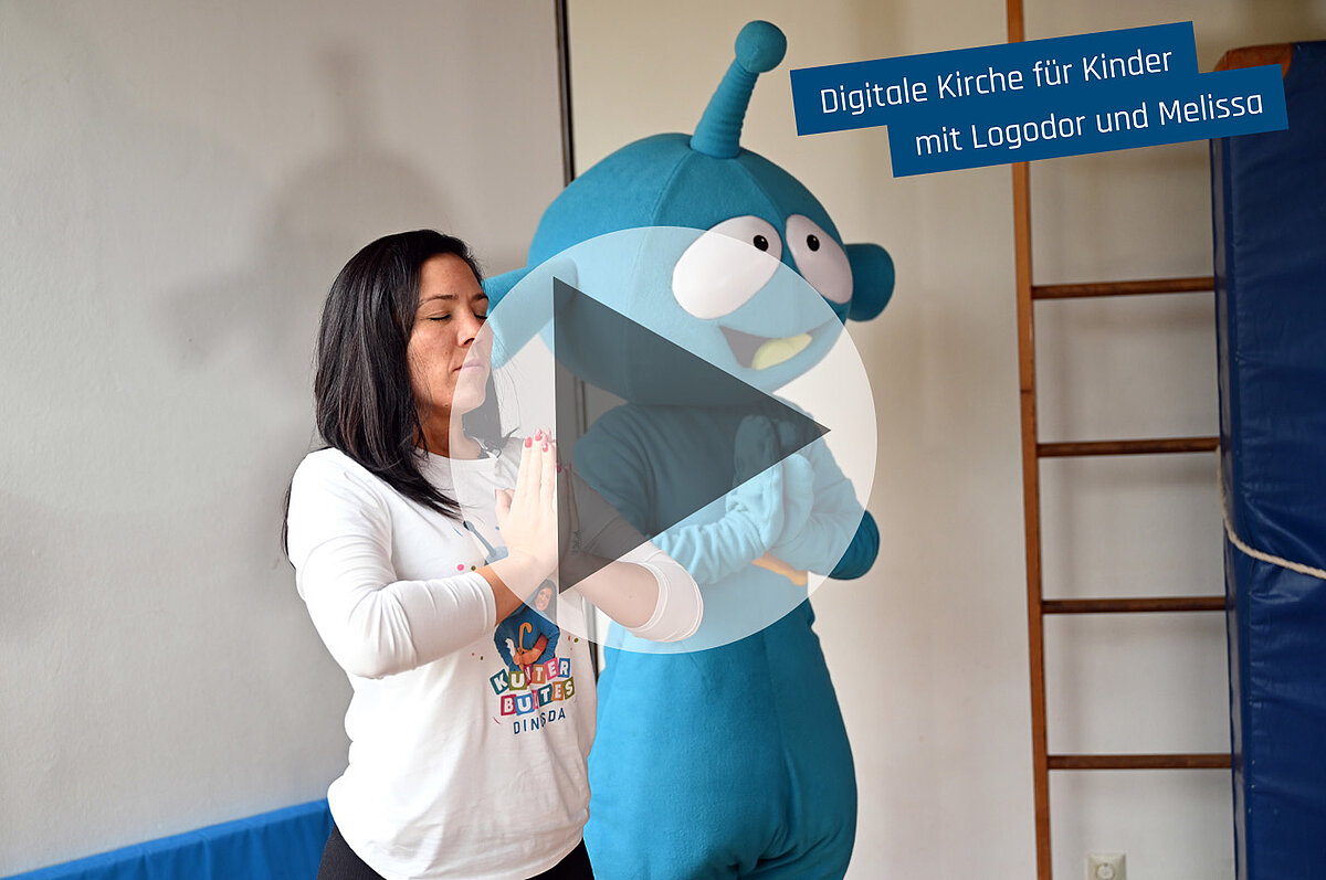 Frau und blaues Maskottchen bereit für "Digitale Kirche für Kinder."