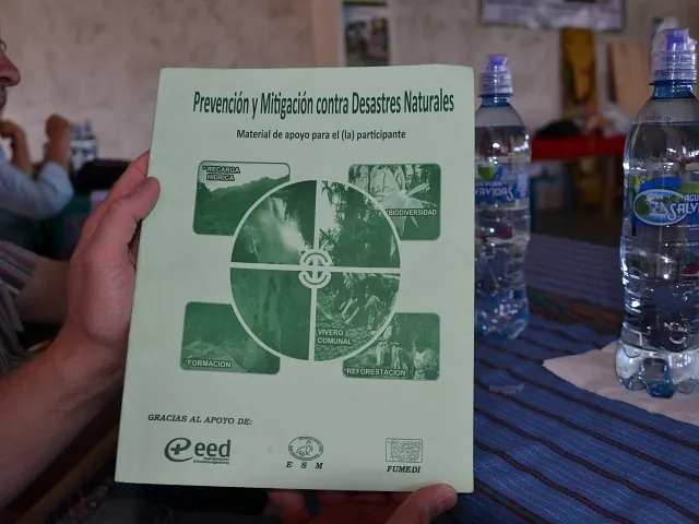 Hände halten grüne Broschüre zur Naturkatastrophenprävention.