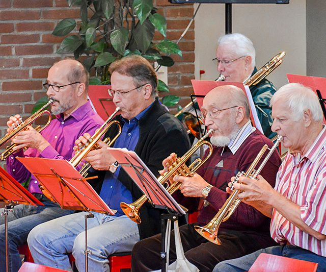 Fünf ältere Männer spielen Trompeten und Posaunen in einer Band.