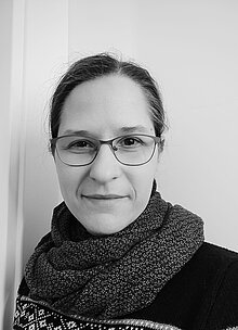 Schwarz-weiß Porträt einer Frau mit Brille und Schal.