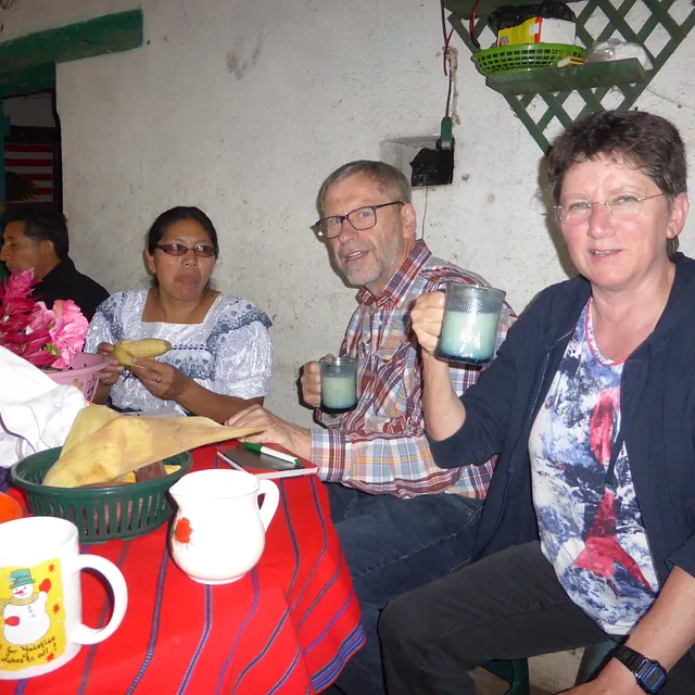 Leute genießen Getränke und Tamales bei einem festlichen Treffen.
